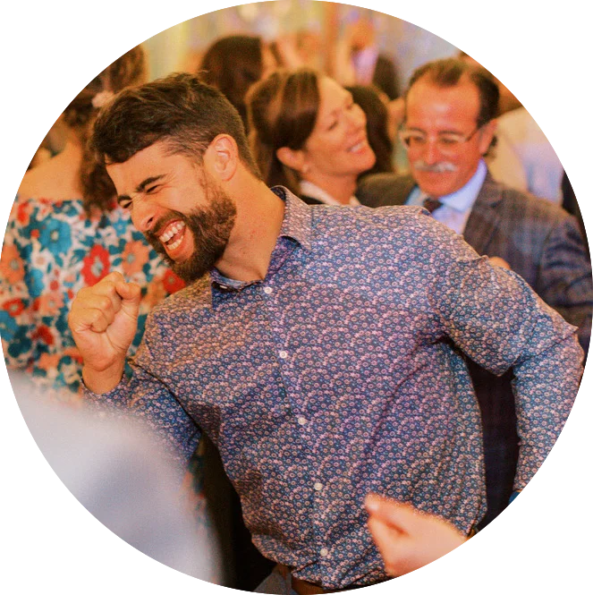 A bearded man laughing at a party, entertained by the Maine DJs.