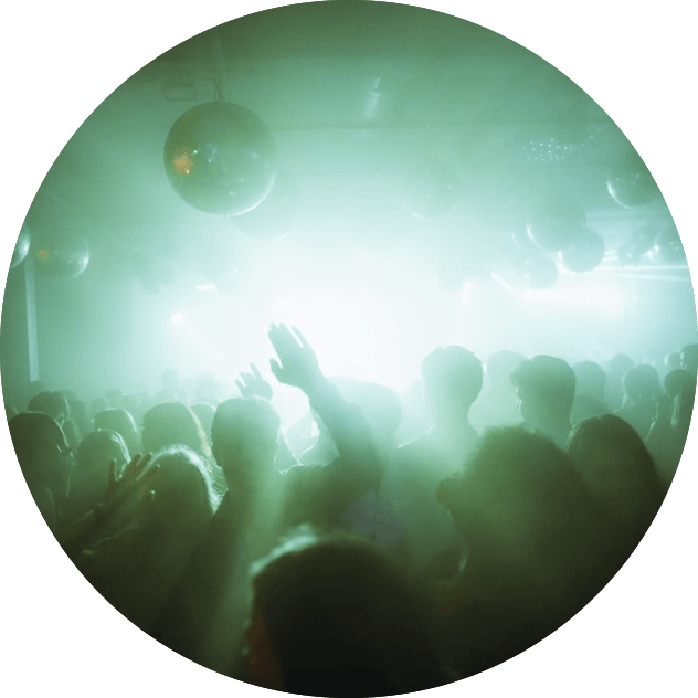 A group of people at a nightclub enjoying the vibrant atmosphere set by ME DJs in the green light.