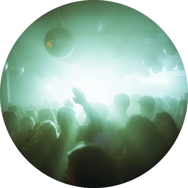 A group of people at a nightclub enjoying the vibrant atmosphere set by ME DJs in the green light.