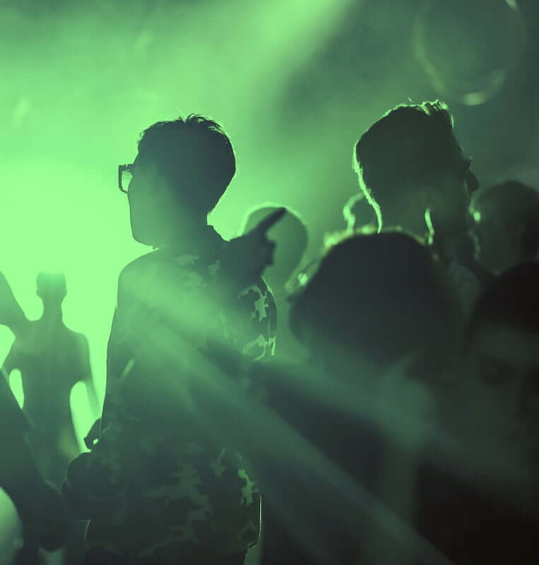 Silhouettes of people at a nightclub in Maine with green lights.